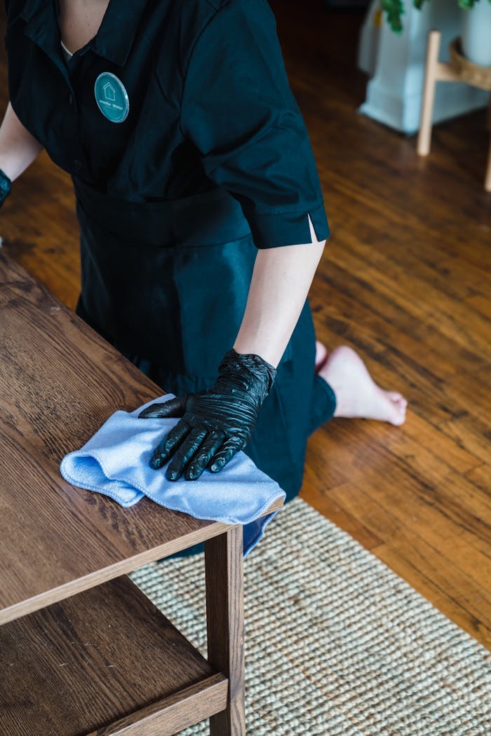 Crafting Captivating Headlines: Your awesome post title goes here A professional cleaner wearing gloves and uniform wipes a wooden table surface indoors.